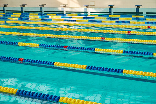 Empty swimming pool with clear blue water and colorful lane dividers. Professional competition lanes in a modern aquatic sports facility