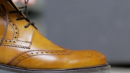 close up shot of a man tying shoelaces on the brown leather shoes