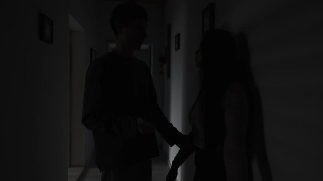 Gaslighting confrontation in dark hallway, tense couple discussion as man holds girlfriend hand