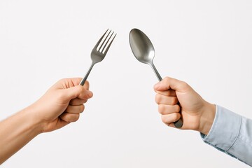 Two hands engaging in a playful culinary clash, presenting a shiny silver fork and spoon against a pristine white background, symbolizing choice and preparation