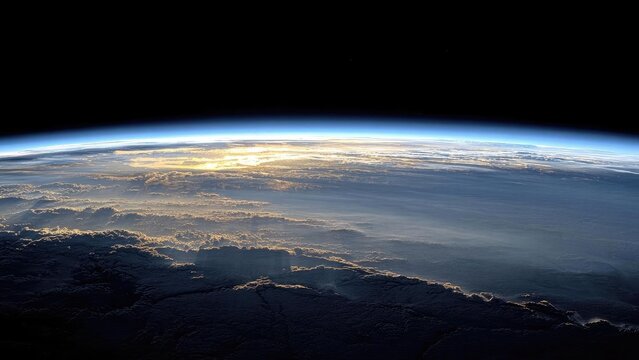 Earth seen from space with a curved horizon, glowing blue atmosphere, and sunlit cloud layers. Concept Earth from space, Curved horizon, Glowing blue atmosphere, Sunlit cloud layers