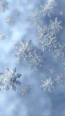 Delicate snowflakes drift gracefully against a soft blue background, creating a serene and wintry atmosphere.