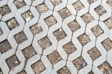 Overhead texture view of a zig-zag patterned concrete paving slab (grass paver) with squares filled...