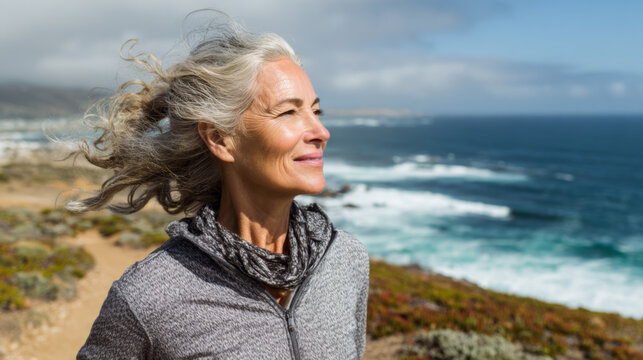 Mature Woman Smiling by the Ocean on a Windy Day