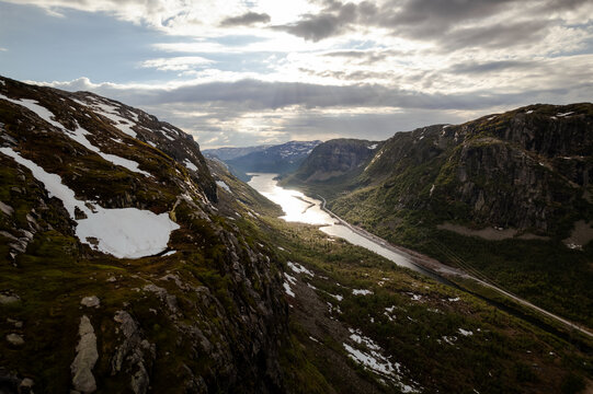 Aerial view of sunlight reflecting off the water between steep, rocky hills, some capped with snow, Dalen, Telemark, Norway.