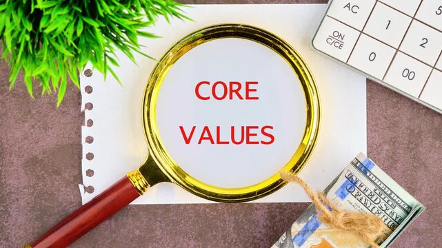 Business and our core values concept. Animation of the CORE VALUES text through a magnifying glass on a piece of paper, top view.