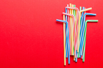 Heap of colorful plastic drinking straws on Colored background, flat lay. Copy Space for text