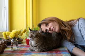A woman with her cat friend at the table in the morning