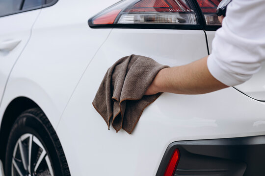 Young man maintaining white electric vehicle with care