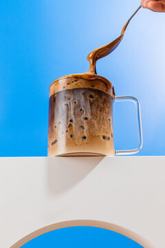 Milky coffee action shot with spoon and glass mug