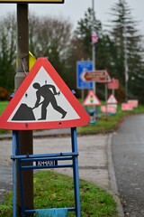 Roadworks Warning Sign on Verge with Multiple Traffic Signs Visible