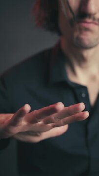 Gesture with hand, mediocre, doubtful: An expressive young Slavic man with a charming appearance and mustache, showcasing emotions through hand gestures and facial expressions in a moody setting.