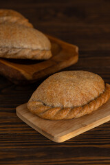 Freshly baked pastries on a wooden board on a table. Russian baked puff pastry with cabbage fillings. Vertical orientation.