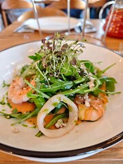 Gourmet seafood salad with shrimp, squid, arugula, microgreens and sauce. Fresh healthy dish, ideal for Mediterranean or fine dining concepts. 