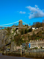 View of the Clifton Suspension Bridge in Bristol, England, with buildings and a river in the foreground.