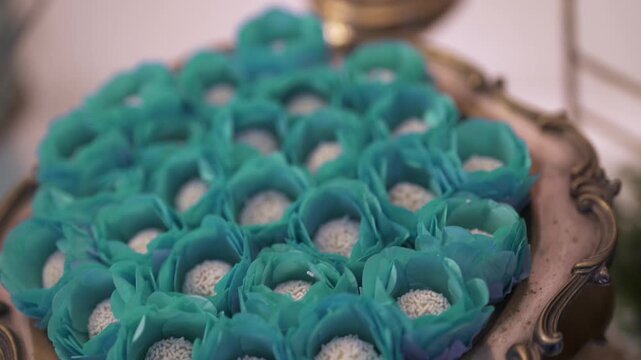 Close-up shot of cupcakes arranged on a decorative tray, with a slight camera movement revealing blue flower-style wrappers.