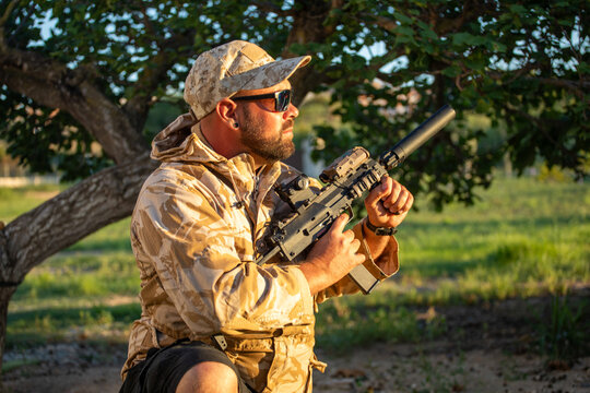Man in camouflage holding airsoft sniper rifle outdoors