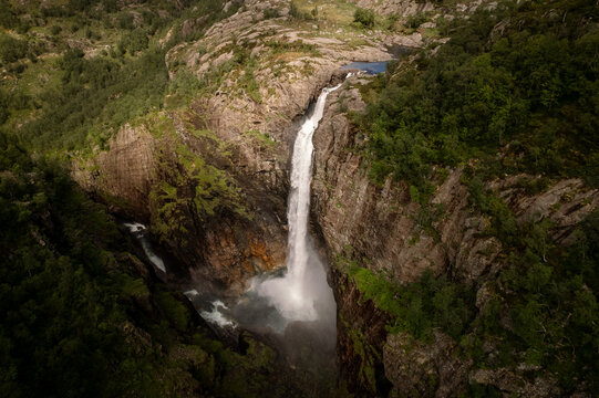 Aerial view of the majestic Manafossen waterfall cascading down rugged cliffs amidst verdant forests, creating a stunning contrast of white water and dark stone, Dirdal, Rogaland, Norway.