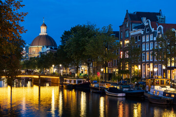 Bridge over the Singel canal illuminated at dusk, with historic houses and the Ronde Lutherse...