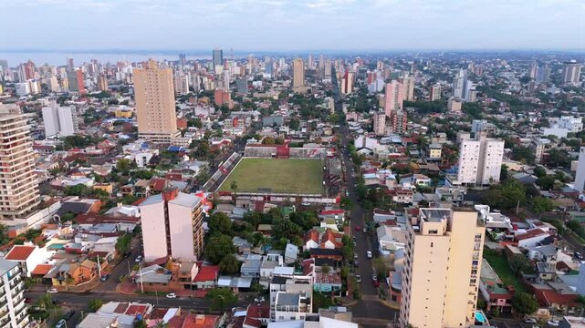 High drone footage over Club Deportivo Guarani Antonio Franco and expansive city of Posadas Argentina, extending until horizon during afternoon.