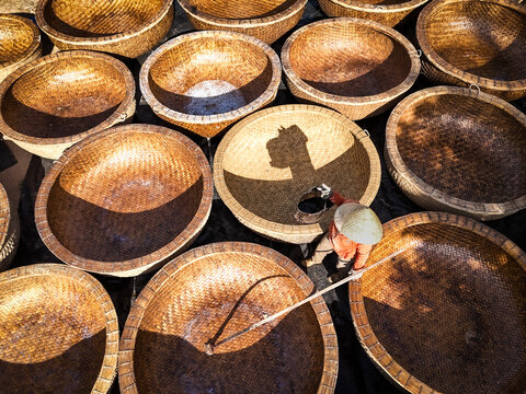 Aerial view of a worker amidst a sea of woven baskets, the sunlight casting shadows that dance across the textures, creating a warm, earthy palette, Ho Chi Minh City, Ho Chi Minh City, Vietnam.