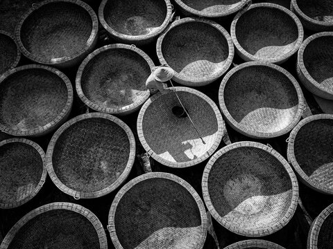 Aerial view of a person with a conical hat amidst the circular baskets, filled with intricate patterns of light and shadow, Ho Chi Minh City, Ho Chi Minh City, Vietnam.
