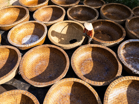 Aerial view of round woven baskets, a sea of textures and warm tones, with a person working, a dance of light and shadow, Ho Chi Minh City, Ho Chi Minh City, Vietnam.