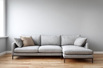 Fototapeta premium Contemporary sectional sofa rests against a neutral gray wall with natural light entering from a side window