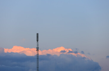 a signal tower against the background of sunset sea of glowing clouds, orange
