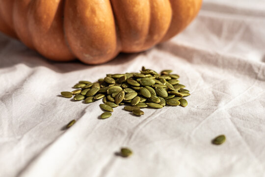 Pumpkin seeds on white fabric with pumpkin backdrop