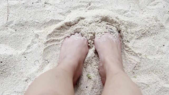 POV Burying bare feet in the fine golden sand, creating a relaxed beach atmosphere
