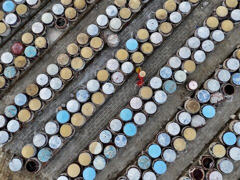 Aerial view of countless colorful containers precisely lined up, creating geometric patterns, a person in red walks amidst them, Ho Chi Minh City, Ho Chi Minh City, Vietnam.