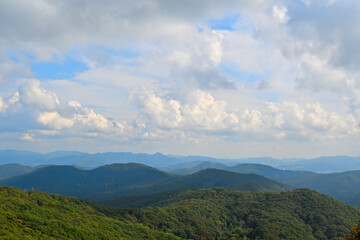 Naklejka premium A mountain range high and wide under a clouded blue sky