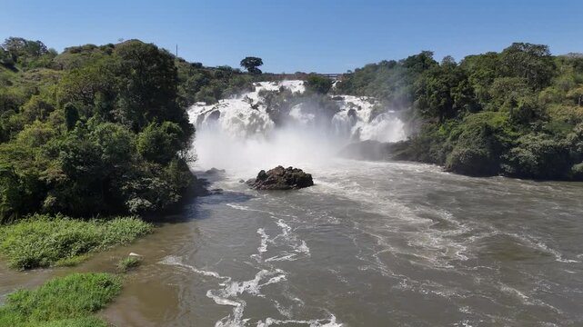 Low-altitude aerial footage of Binga Falls, Angola, showing the lower cascades and fast river currents blending with sunlight and tropical greenery