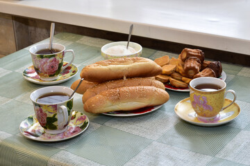 There are cups of tea and a plate of buns on the table.