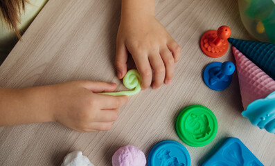 A little girl makes figurines out of colored airy plasticine, modeling dough. Hobbies for...