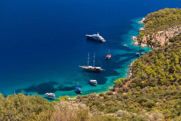 Aerial shot of a tranquil bay where several boats and yachts rest near a rocky coast