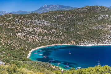 A stunning turquoise bay sheltered by rugged hills, dotted with sailboats. Firnaz bay