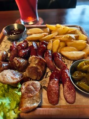 Irish sausages with potato wedges, jalapeno and dipping sauce served on a rustic wooden board in a pub setting. Warm, hearty comfort food with a classic European pub vibe. 
