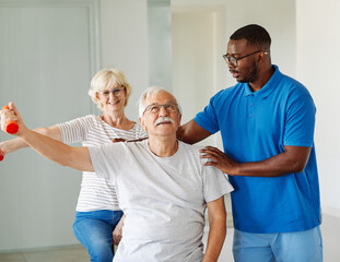 Doctor or nurse or physiotherapist caregiver exercise with senior couple at clinic or nursing home
