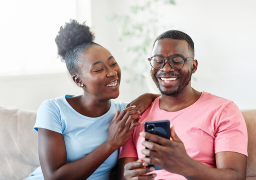 Happy young couple having fun using smartphone  during oline video call conversation or shopping or using an app at home - Powered by Adobe