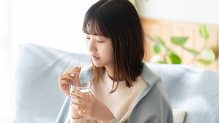 薬を飲む体調不良の女性