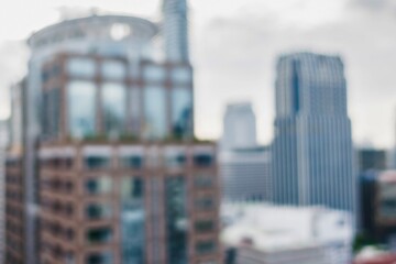 Blurry cityscape with tall modern buildings under a cloudy sky