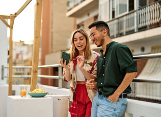 Portrait of a young happy couple having fun taking a selfie with camera on smartphone outdoors. Girlfriend and boyfriend bonding, love concept during summer.