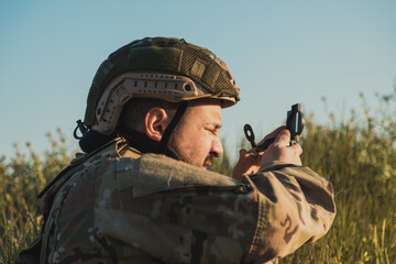 Fototapeta premium Soldier Looking At The Compass While In A Field 