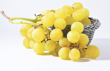 Bunch of yellow grapes in a grey basket on a white background.	