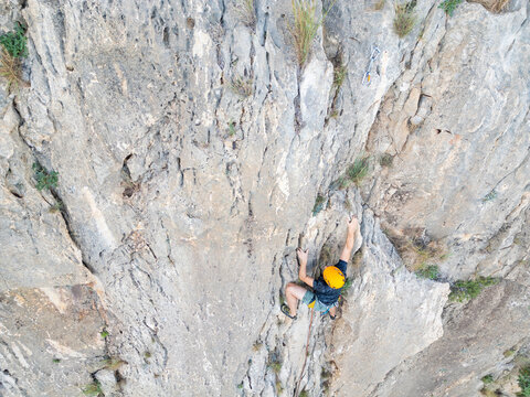 Climbers tackle vertical rock face with helmet and rope