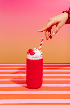 Raspberry smoothie with whipped cream and hand reaching