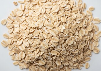 A close up overhead view of a pile of rolled oats on a white background