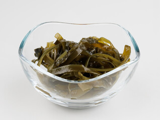 Seaweed salad in a glass cup on a white background.